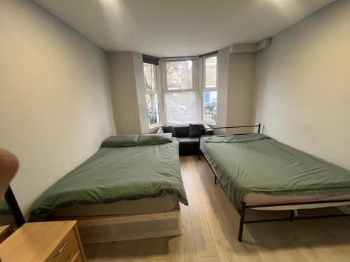Habitación con 2 camas y sofá. en Sterne Street 4 Person Room, en Londres