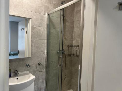a bathroom with a glass shower and a sink at Sterne Street 4 Person Room in London