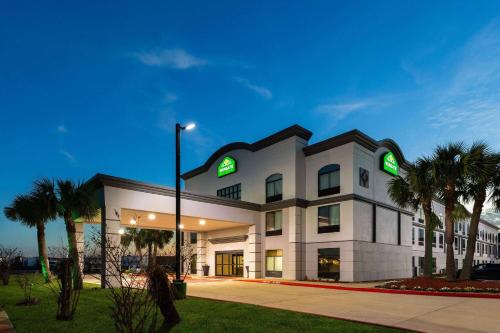 a large white building with green lights on it at Wingate by Wyndham Sulphur Near Lake Charles in Sulphur