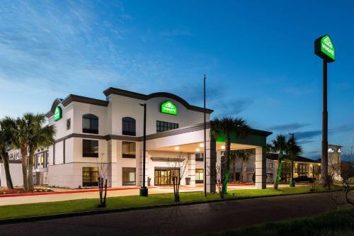 a large white building with green lights on it at Wingate by Wyndham Sulphur Near Lake Charles in Sulphur