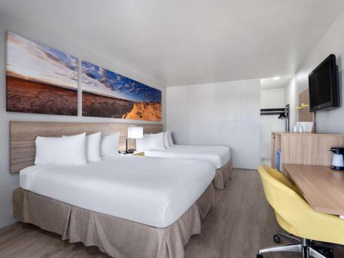 a hotel room with two beds and a desk at Days Inn by Wyndham Las Vegas Airport Near the Strip in Las Vegas