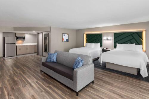 a hotel room with two beds and a couch at Wingate by Wyndham Sulphur Near Lake Charles in Sulphur