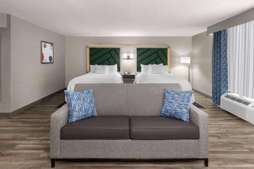a living room with a couch and two beds at Wingate by Wyndham Sulphur Near Lake Charles in Sulphur