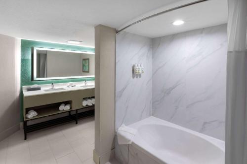 La salle de bains est pourvue d'une baignoire et d'un lavabo. dans l'établissement Wingate by Wyndham Sulphur Near Lake Charles, à Sulphur