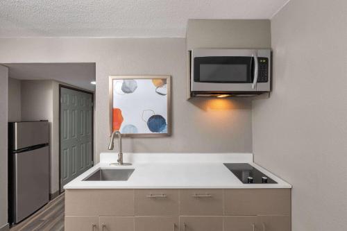 a kitchen with a sink and a microwave at Wingate by Wyndham Sulphur Near Lake Charles in Sulphur