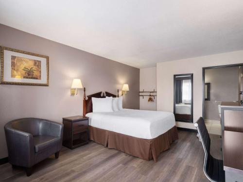 Habitación de hotel con cama y silla en Travelodge by Wyndham Tucson AZ en Tucson