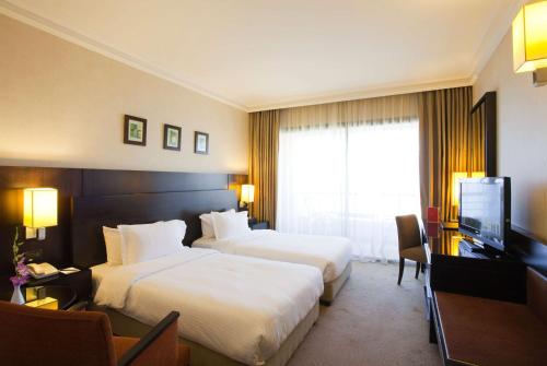 um quarto de hotel com duas camas e uma televisão de ecrã plano em Ramada Plaza by Wyndham Beirut Raouche em Beirute