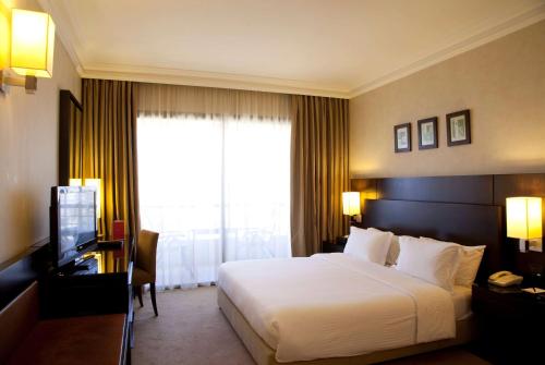 a hotel room with a bed and a television at Ramada Plaza by Wyndham Beirut Raouche in Beirut