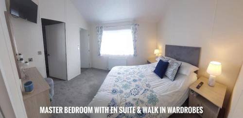a bedroom with a bed with blue pillows and a window at Greenshaw - extremely spacious in Rye Harbour