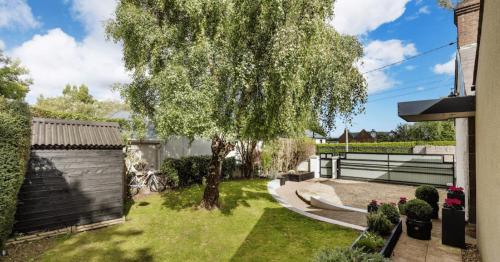 a garden with a tree and a fence at GuestReady - Opulence Malahide Seaside Cottage in Malahide