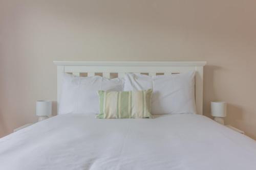 a white bed with two pillows and two lamps at GuestReady - A charming place near Golf Centre in Dublin