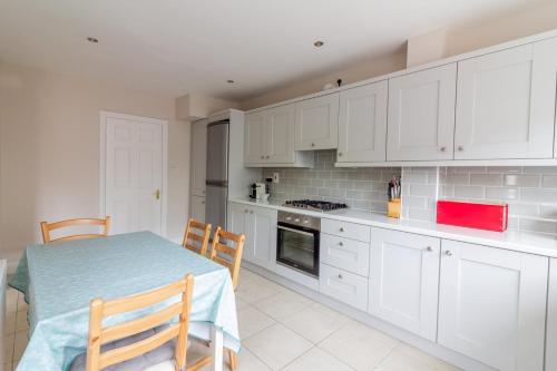 a kitchen with white cabinets and a table and chairs at GuestReady - A charming place near Golf Centre in Dublin