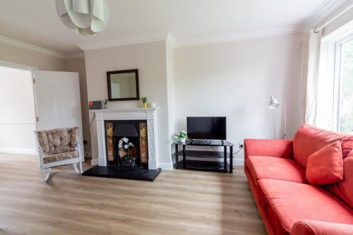 a living room with a red couch and a fireplace at GuestReady - A charming place near Golf Centre in Dublin