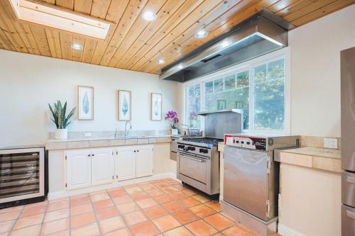 a large kitchen with stainless steel appliances and a wooden ceiling at Casteel - 4,500 sq-ft retreat with a pool and hot tub in the middle of wine country! in Templeton