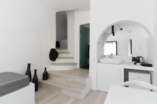 ein weißes Badezimmer mit einem Waschbecken und einem Spiegel in der Unterkunft Mill Houses New Elegant Suites in Firostefani