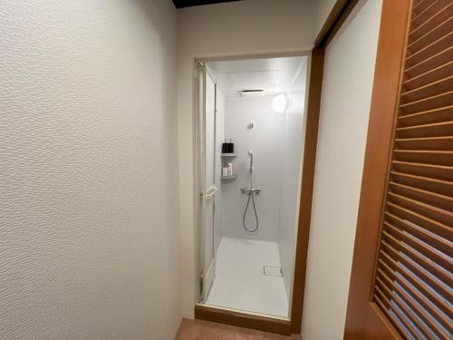 a bathroom with a shower with a mirror at ゲストハウス JOOOY Hotel 奄美 in Amami