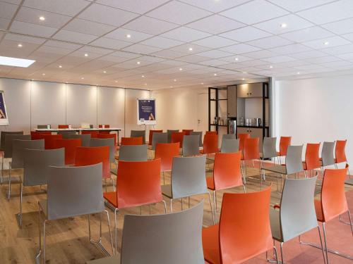 una sala de conferencias con sillas de color naranja y blanco en ibis budget Nice Californie Lenval, en Niza