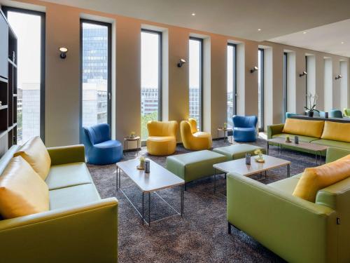 a waiting room with couches and tables and windows at Aparthotel Adagio Bremen City in Bremen
