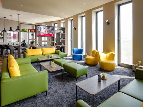 a living room with green couches and tables at Aparthotel Adagio Bremen City in Bremen
