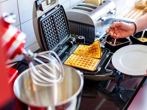 Eine Person bereitet Essen in einer Küche zu in der Unterkunft Aparthotel Adagio Bremen City in Bremen