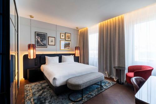 a hotel room with a bed and a red chair at Radisson Collection Hotel, Santa Sofia Milan in Milan