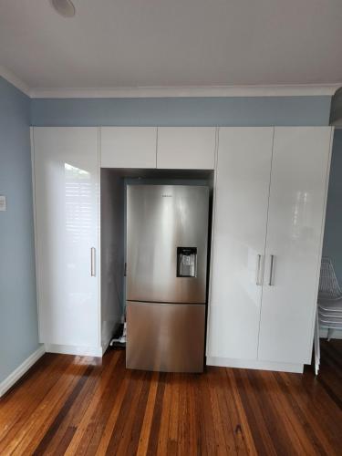 a kitchen with white cabinets and a stainless steel refrigerator at OXLEY Mineral Pool & Private Home suburbanSTAY in Brisbane