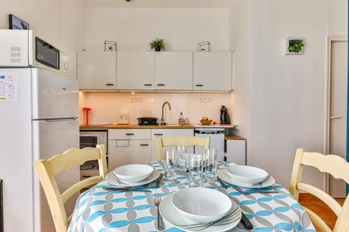 a kitchen with a table with chairs and a white refrigerator at Résid'Azur - T2 résidentiel avec piscine in Saint-Jean-de-Monts