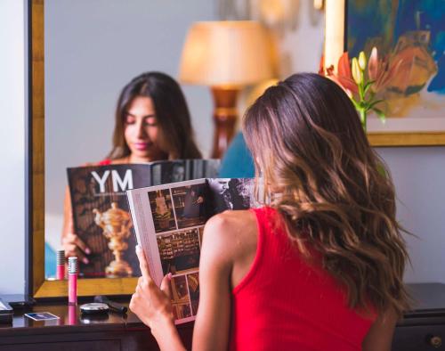 uma mulher a ler uma revista em frente a um espelho em Kempinski Nile Hotel, Cairo no Cairo