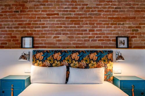 een slaapkamer met een bed en een bakstenen muur bij Factory Apartments Barcelona in Barcelona