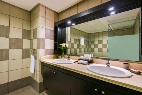 ein Badezimmer mit zwei Waschbecken und einem großen Spiegel in der Unterkunft Kempinski Residences & Suites, Doha in Doha