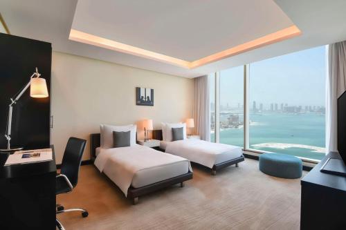 a hotel room with two beds and a large window at Kempinski Residences & Suites, Doha in Doha