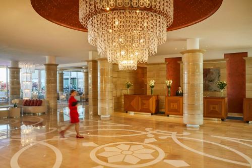 een vrouw die door een lobby loopt onder een kroonluchter bij Kempinski Hotel Adriatic Istria Croatia in Savudrija