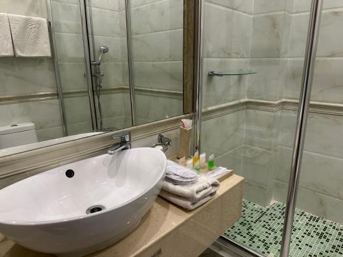 y baño con lavabo blanco y ducha. en Royal, en Aktobe