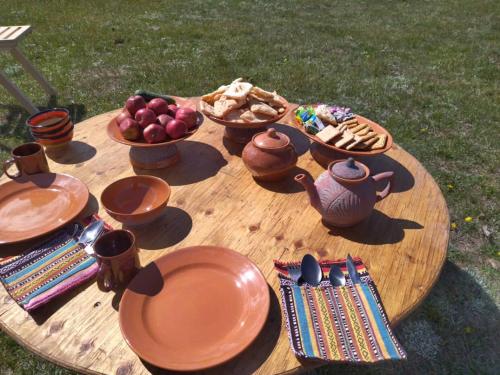 einem Holztisch mit Tellern und Schalen mit Lebensmitteln darauf in der Unterkunft Tunduk son-kol yurt camp in Song-Kul