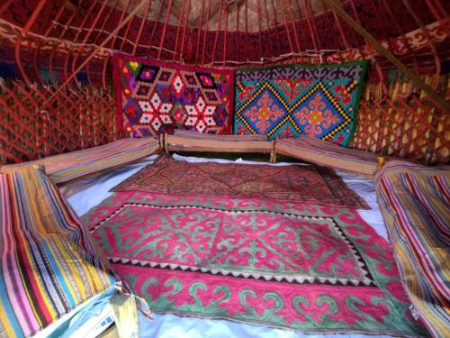 Bett in einem Zelt mit bunten Decken und Kissen in der Unterkunft Tunduk son-kol yurt camp in Song-Kul