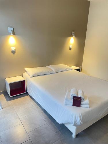 a bedroom with a bed with a book and a tv at Hôtel Némo Aéroport de Pau - KB HOTEL GROUP in Sauvagnon