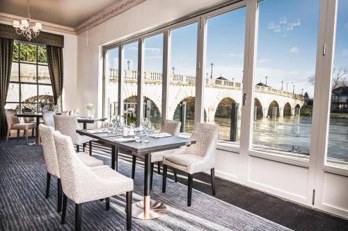 uma sala de jantar com mesa e cadeiras e vista para uma ponte em Thames Riviera Hotel, Sure Hotel Collection by Best Western em Maidenhead