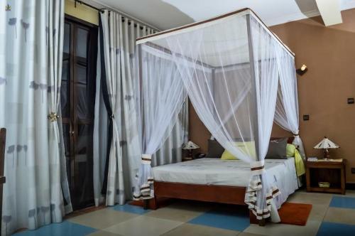 een slaapkamer met een hemelbed en witte gordijnen bij HOTEL LE GRAND PALAIS in Fianarantsoa
