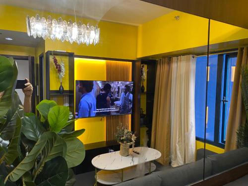 a room with a tv and a couch and a table at Laugh and Lounge 2 Bedroom Luxury Condo Air residence Makati in Manila