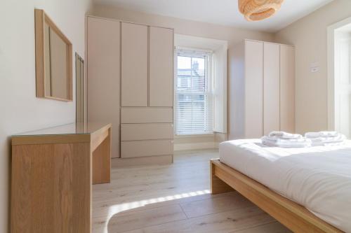 a white bedroom with a bed and a dresser at GuestReady - Relax and Explore in Dundrum in Dublin