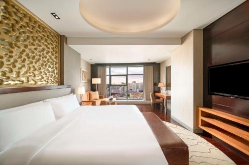 a bedroom with a large bed and a flat screen tv at Kempinski Hotel Taiyuan in Taiyuan
