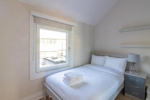 - une chambre avec un grand lit blanc et une fenêtre dans l'établissement GuestReady - Cosy Retreat in Donnybrook, à Dublin