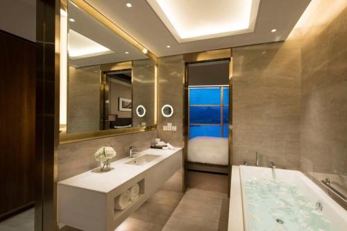 - Baño con 2 lavabos, bañera y cama en Sunrise Kempinski Hotel Beijing, en Huairou