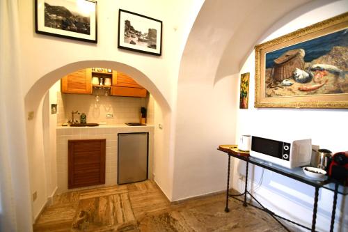 a kitchen with an archway and a counter with a microwave at Villa Castello Apartments in Capri