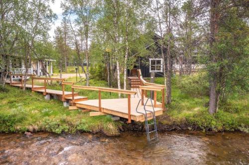 eine Holzbrücke über einen Fluss mit Bäumen in der Unterkunft Wilderness Hotel Muotka & Igloos in Saariselkä