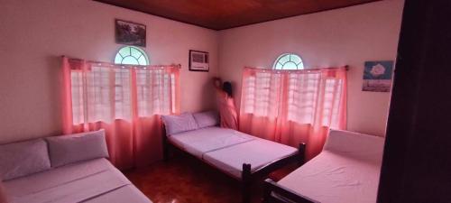 a room with two beds and two windows at Camille's Cheapstay in Alaminos