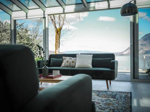 un salon avec un canapé et une grande fenêtre dans l'établissement Venez Chez Vous Les Pieds dans l'Eau, à Sévrier