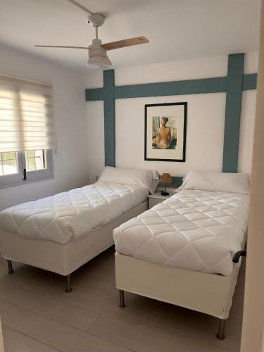 2 Betten in einem Schlafzimmer mit Deckenventilator in der Unterkunft Villa Portitxol en Moraira in Moraira