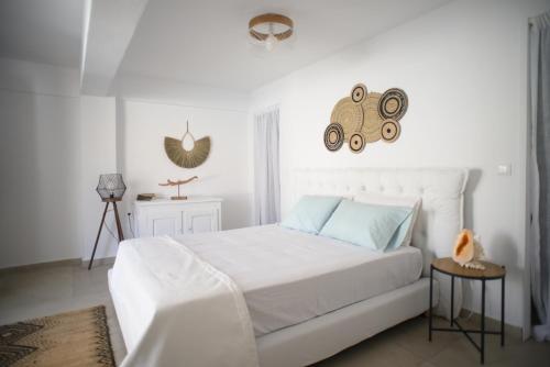 a white bedroom with a white bed with blue pillows at Onar Loutra, Kythnos in Loutrá