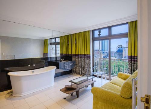 een grote badkamer met een bad en een groot raam bij Hyatt Regency Harare The Meikles in Harare
